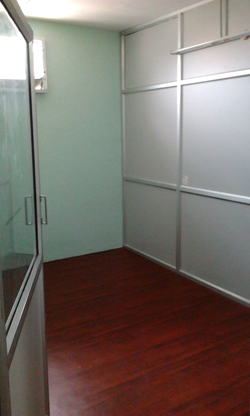 An office room with a glass door, partition panels and a wood-finish floor