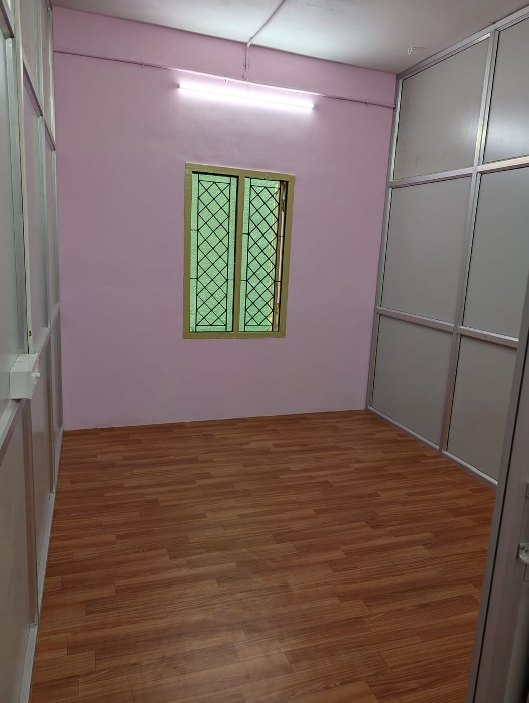 Room with a window, partition panels and a wood-finish floor